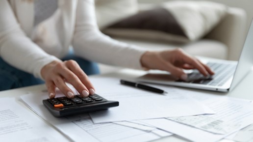 Comptable en train de travailler sur une calculatrice et sur son logiciel de GED pour dématérialiser ses documents comptables